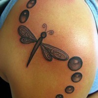 Black dragonfly tattoo on shoulder