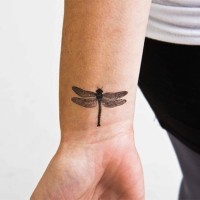 Schwarzgraues Libelle-Tattoo am Handgelenk