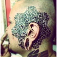 Schwarzgraues Tattoo mit Ornament auf dem Gesicht
