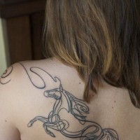 Black horse silhouette tattoo on shoulder blade