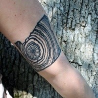 Black ink arm tattoo of crossed section of the tree