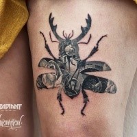 Black ink awesome looking thigh tattoo of large bug stylized with roses