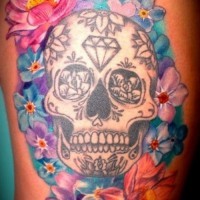 Tatuaje en el muslo,  calavera de azúcar de color blanco con flores diferentes vistosas