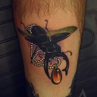 Black ink bug with medallion tattoo on leg