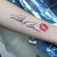 Black ink celebrity signature and red lip imprint tattoo on forearm