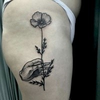 Black ink engraving style thigh tattoo of human hand holding flower