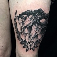 Black ink engraving style thigh tattoo of horse skeletons with leaves