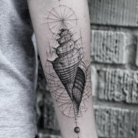Black ink forearm tattoo of small shell with ornaments