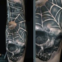 Black ink impressive looking human skull with spider web tattoo on elbow