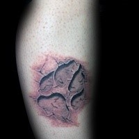 Black ink leg tattoo of medium size paw print