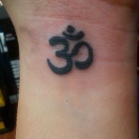 Black ink om symbol tattoo on wrist