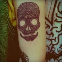 Schwarzes Tattoo von gemustertem Totenkopf am Unterarm
