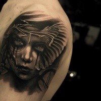 Black ink shoulder tattoo of woman with mask
