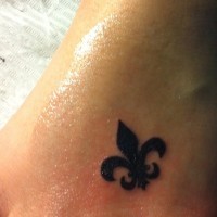 Tatuaje en el pie,
 flor de lis negra diminuta