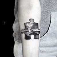 Black ink small funny looking puzzle piece tattoo on arm stylized with sea sights