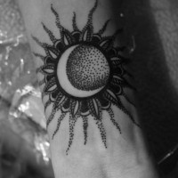 Black ink sun with moon tattoo on wrist