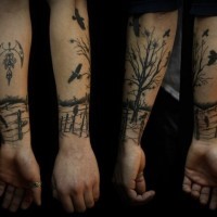 Tatuaje en el antebrazo,
árbol con valla  y aves, tinta negra