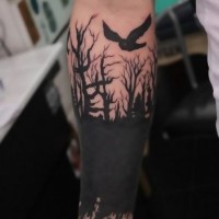 Black ink trees and bird forearm tattoo