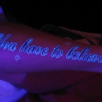 Black light inscription on the arm tattoo