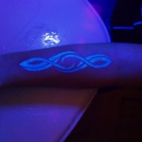 tribale luce nera su braccio tatuaggio