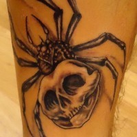 Black spider and skull tattoo on leg