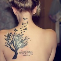 Tatuaje en la espalda de un árbol negro con pájaros.