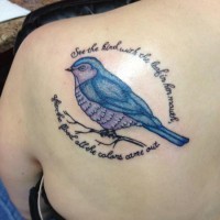 Tatuaje en el hombro, pájaro y inscripción en torno de él
