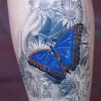Tatuaggio colorato sulla gamba la farfalla blu tra i fiori