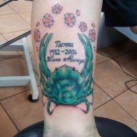 Tatuaje en la pierna, cangrejo  verde con fecha y flores suaves
