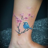 carino colorato uccello blu su ramo di albero fiorito tatuaggio su caviglia