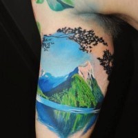 Breathtaking natural looking and colored big mountain lake tattoo on arm