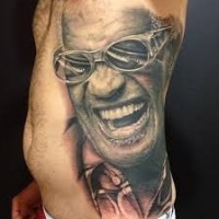 Tatuaje en el costado,  cantante famoso sonriente en gafas de sol