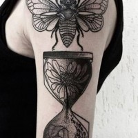 Tatuaje en el brazo, polilla  y reloj de arena