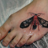 Tatuaggio colorato 3D sul piede la farfalla nera rossa