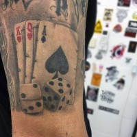 Tatuaje en el brazo, naipes con dados,  tema de los juegos de azar