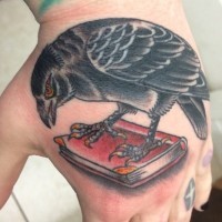Cartoon like colored crow tattoo with book on hand