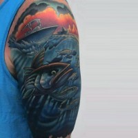 Tatuaje colorido en el hombro,
 barco pesquero y bandada de peces
