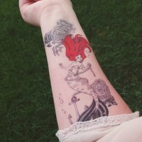 Cartoon like painted red-head mermaid tattoo on forearm with roped anchor and flowers
