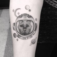 Cartoon style black and white space cat tattoo on forearm stylized with planets