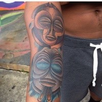 Cartoon style colored arm tattoo of funny looking tribal masks