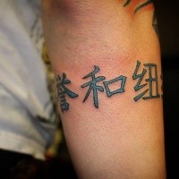 Cartoon style colored Asian lettering tattoo on arm