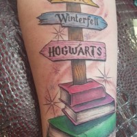 Cartoon style colored forearm tattoo of fantasy road sign with books