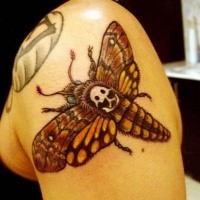 Cartoon style colored shoulder tattoo of big butterfly with human skull