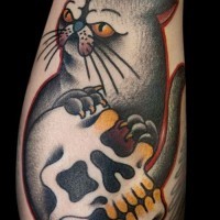 Cat with skull in paws tattoo on leg