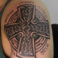 Tatuaje en el brazo, cruz celta de piedra y cita