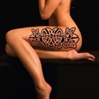 Celtic style black and white flower shaped tattoo on thigh