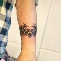 Celtic style black ink arm tattoo on arm