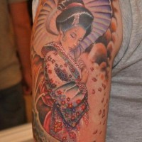Charming shy Asian Geisha in floral kimono with umbrella tattoo on arm with floral petals