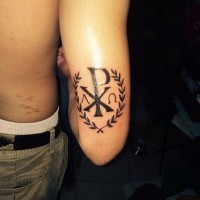 Tatuaje en el brazo, monograma de Cristo precioso con corona de laurel