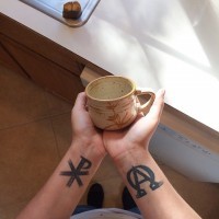 Chi Rho besonderes Christus Monogramm und religiöses spezielles Symbol dunkles schwarzes Tattoo an beiden Handgelenken